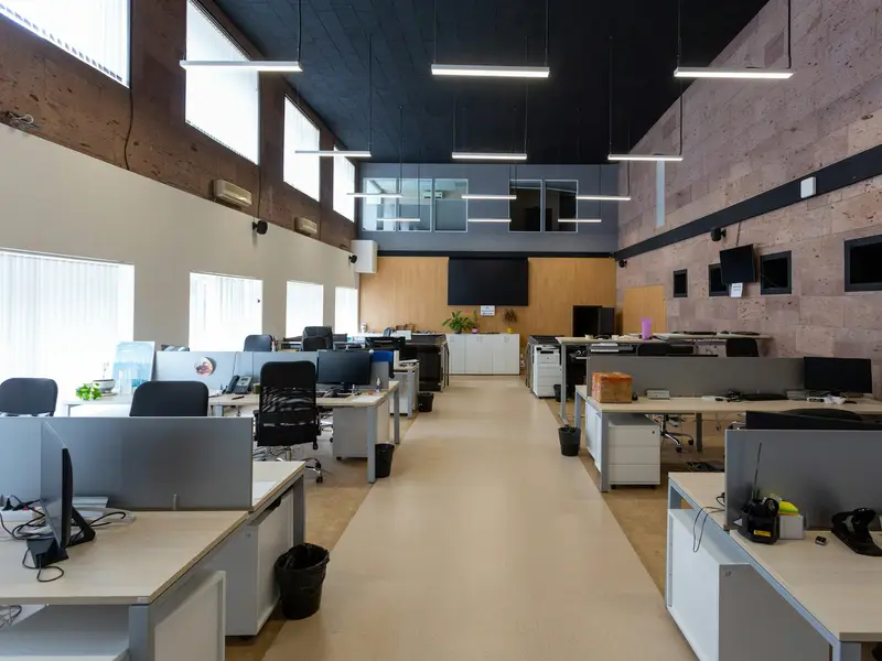 A large commercial workspace with rows of desks under linear ceiling lights