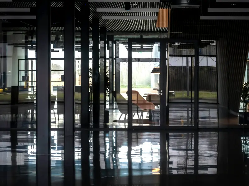 A glass-walled office common area with a freshly polished, reflective floor