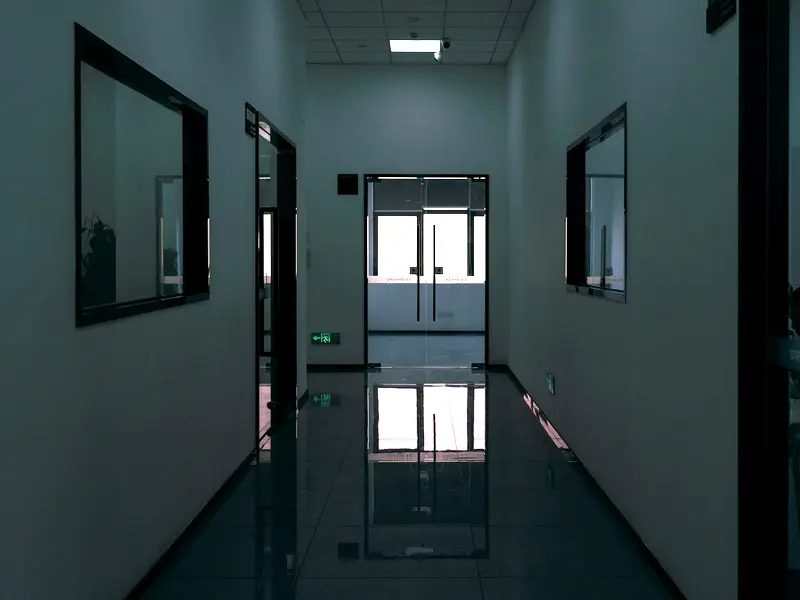 A dark office corridor with a hard floor polished to a mirror finish